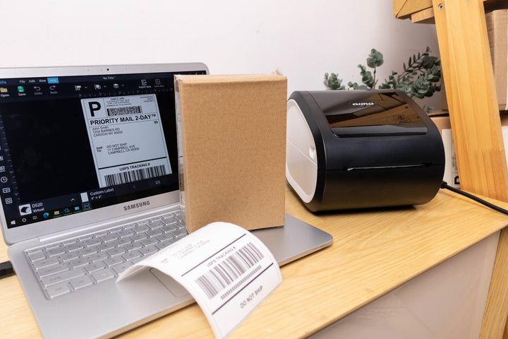 Dabbous Mega Supplies AIMO D520BT thermal printer printing shipping labels next to laptop and cardboard box